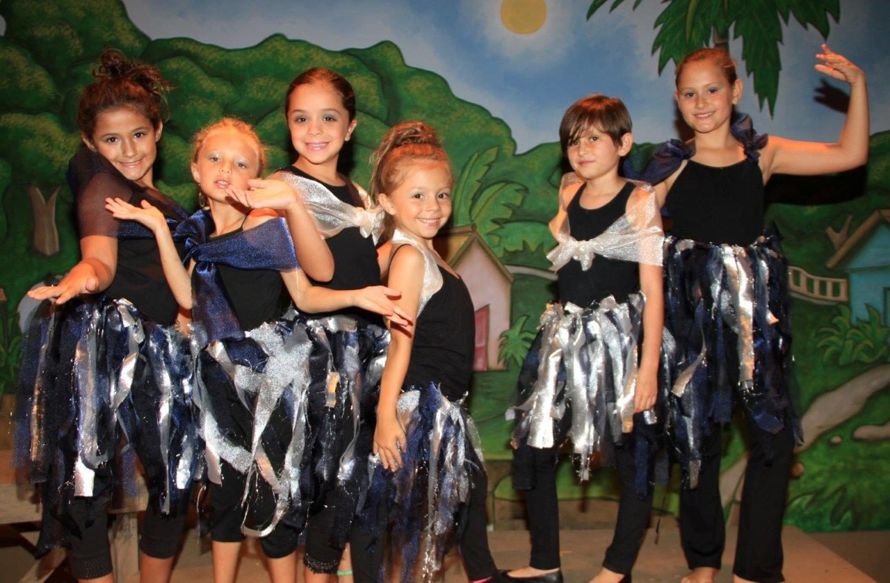 Dancers in tattered skirts on a tropical set