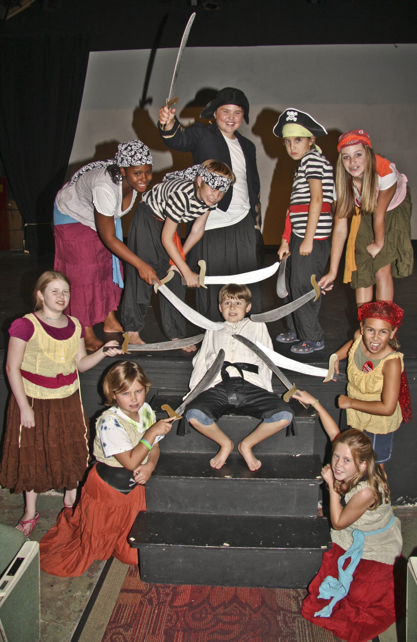 A pirate cast posing on the stage steps