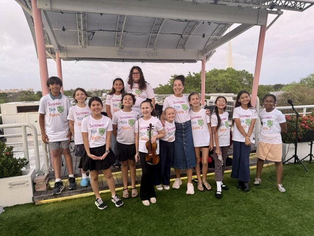 The orchestra in Southernmost Youth Orchestra T-shirts in front of the stage