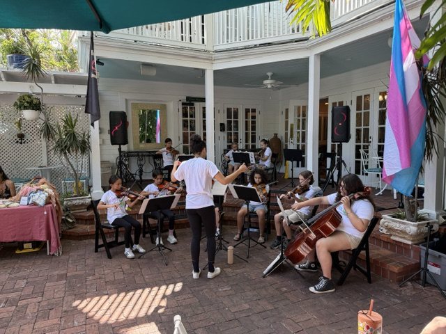The orchestra plays in a courtyard, led by its conductor